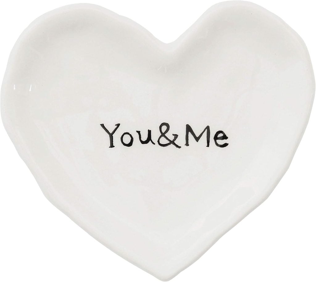 A white ceramic dish shaped like a heart with the words "You & Me" printed in black in the center.