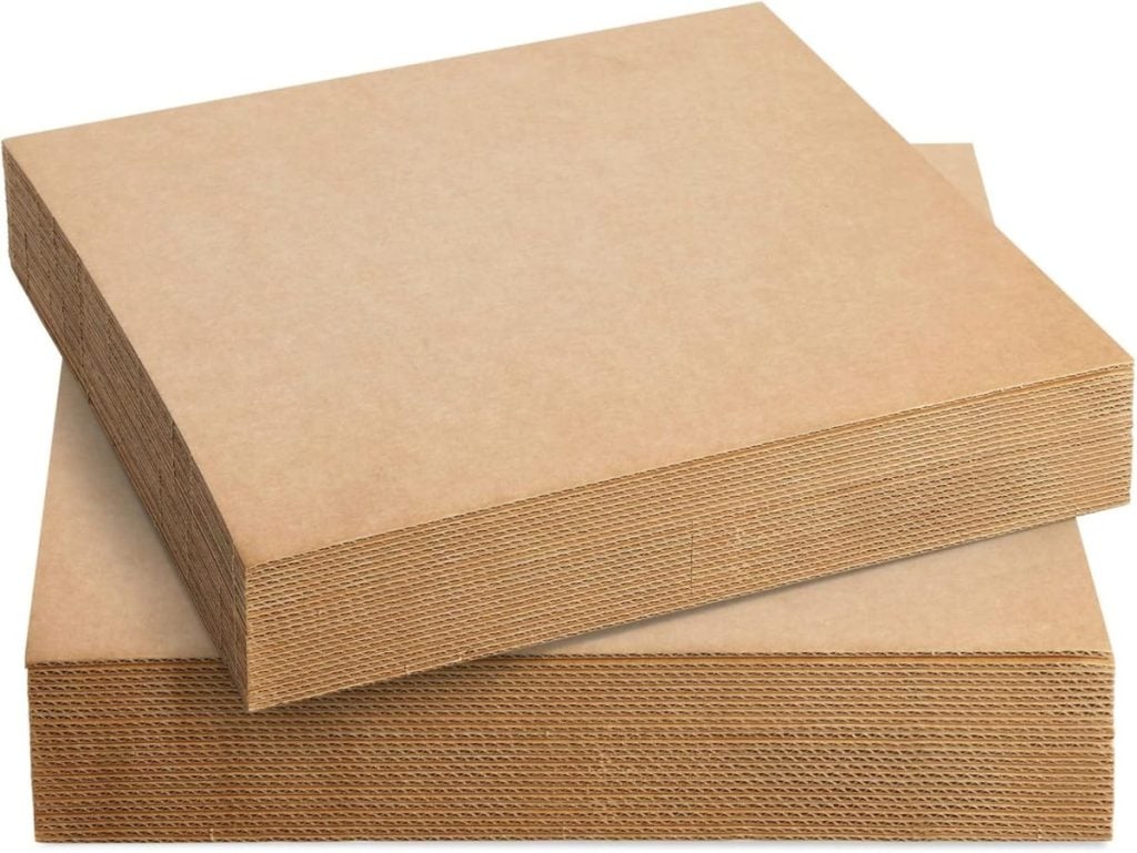 Two stacks of square, brown corrugated cardboard sheets are placed on a white background.
