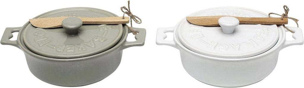 Two ceramic baking dishes with lids, one gray and one white, each topped with a wooden spreader tied with string.