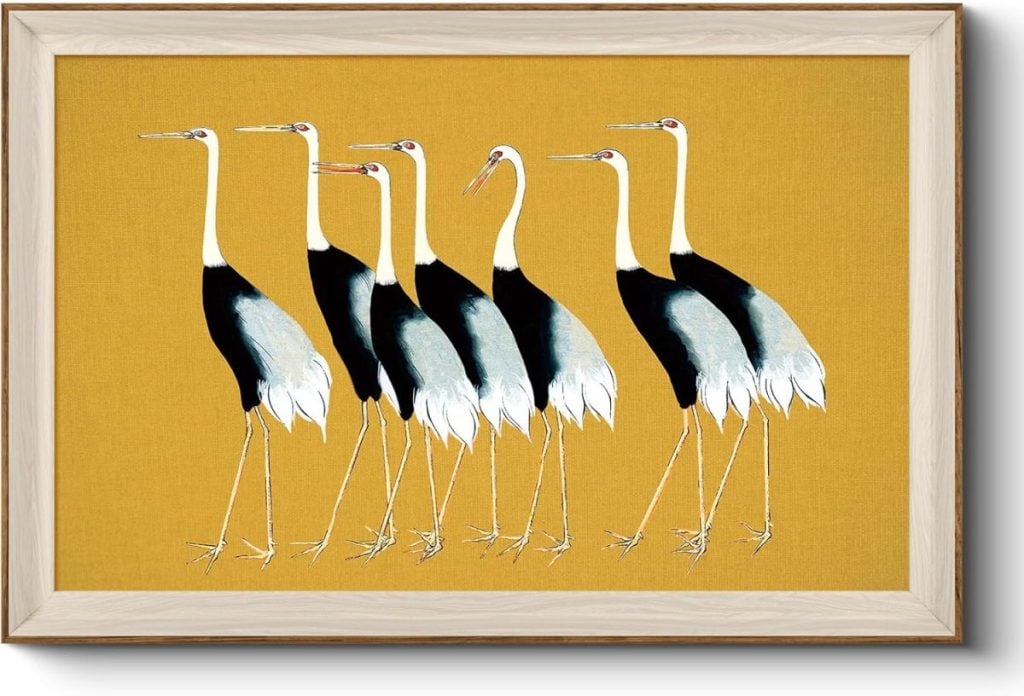 Framed artwork depicting six stylized cranes with black, white, and gray plumage standing against a mustard yellow background.
