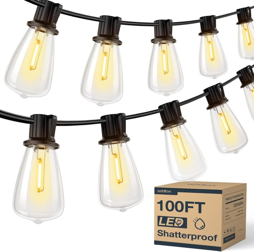 String of yellow-tinted LED outdoor lights with black sockets; product box in foreground labeled "100FT LED Shatterproof." Brighten up your patio and add to your list of Things To Do This Year with these durable, stylish lights.
