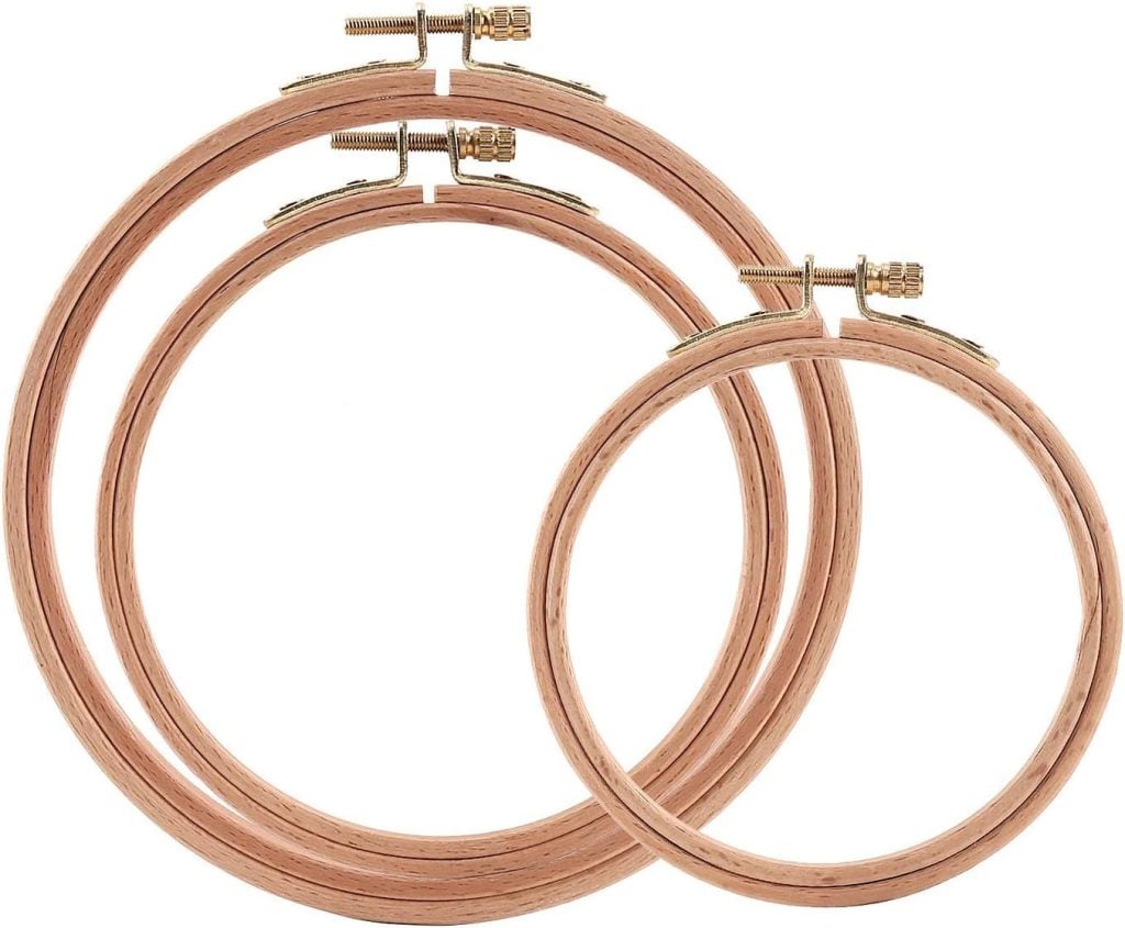 Two wooden embroidery hoops of different sizes, each with a metal screw fastener at the top for adjusting tightness.