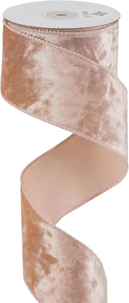 A spool of wide, light pink velvet ribbon with a wired edge, partially unrolled in a spiral shape.