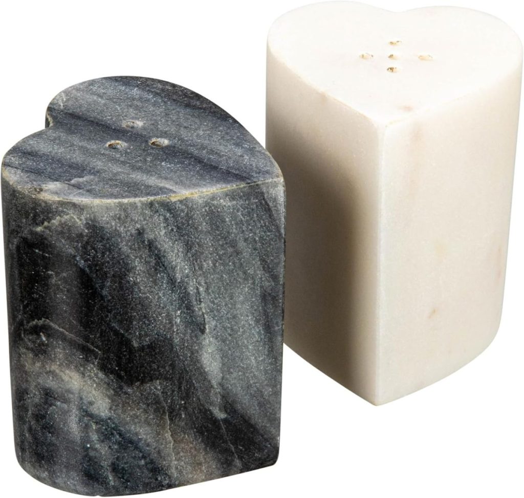 A pair of heart-shaped salt and pepper shakers, one made of dark marble and the other of light marble, placed side by side.