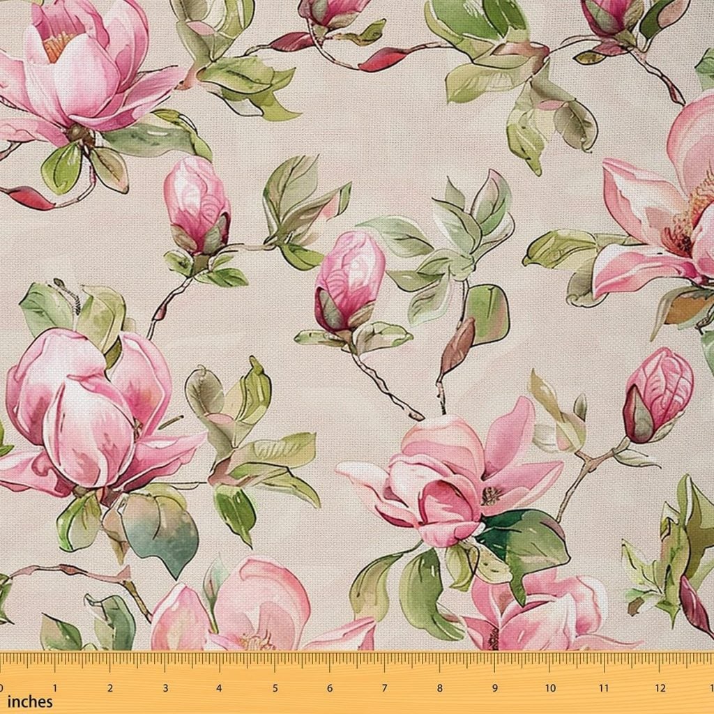 A fabric with a pattern of pink magnolia flowers and green leaves on a beige background; a yellow ruler at the bottom shows measurements in inches.