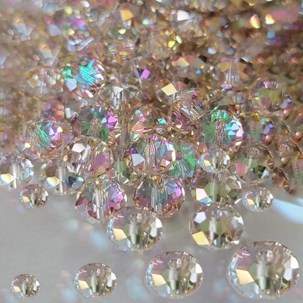 A collection of faceted, iridescent crystal beads reflecting various pastel colors under a light source.