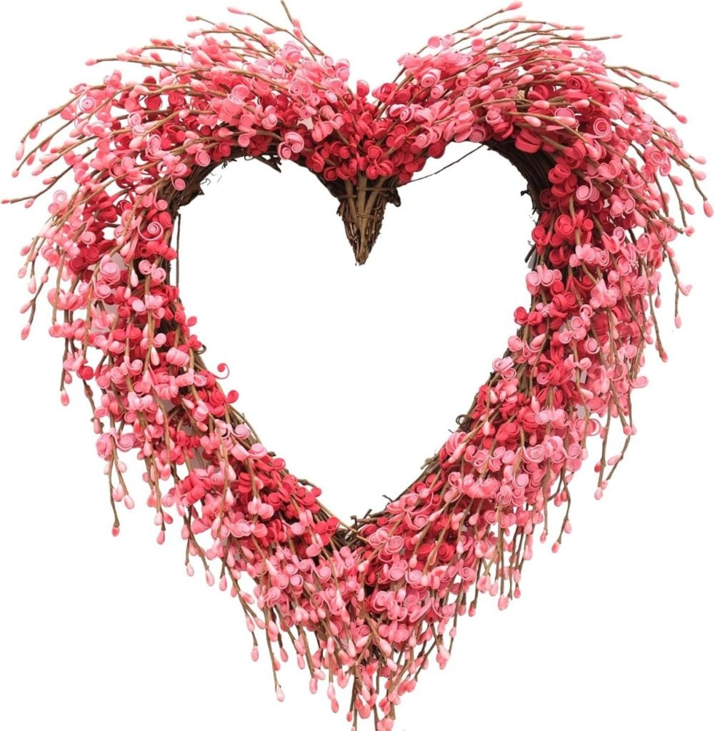 A heart-shaped wreath made of intertwined twigs and decorated with clusters of small pink buds.