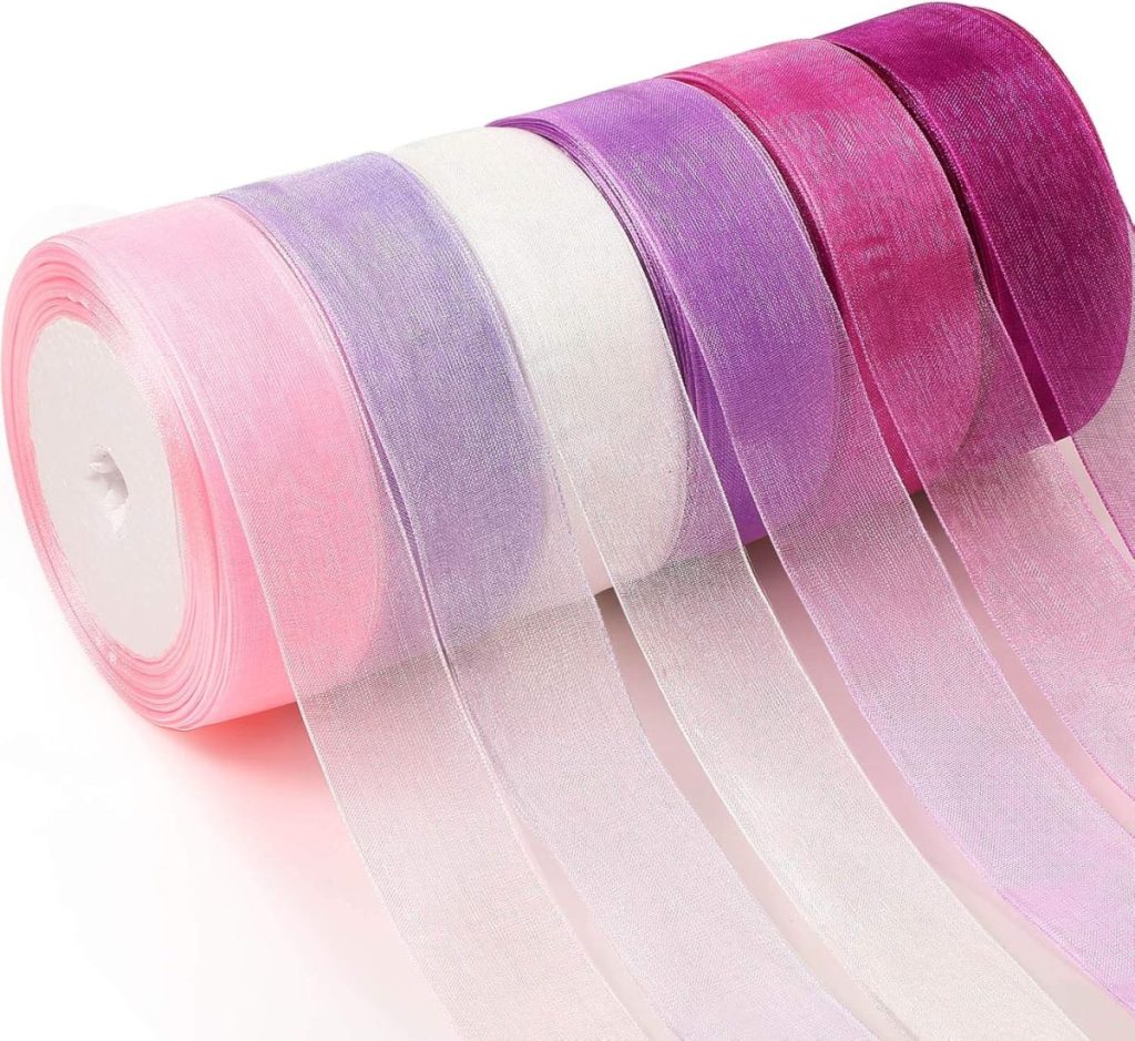 Five rolls of sheer organza ribbon are arranged in a row, each roll featuring a different color gradient from pink to purple and white.