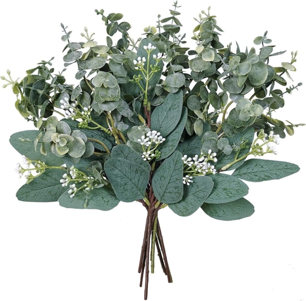A bouquet of artificial eucalyptus stems with round green leaves, small white berries, and multiple brown stems bundled together&mdash;perfect for sprucing up your space as one of the things to do this year.