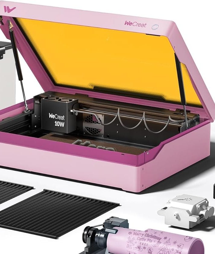 A pink laser engraver and accessories are shown, along with sample engraved items: a mug, earrings, a Christmas sign, and a decorative scene.