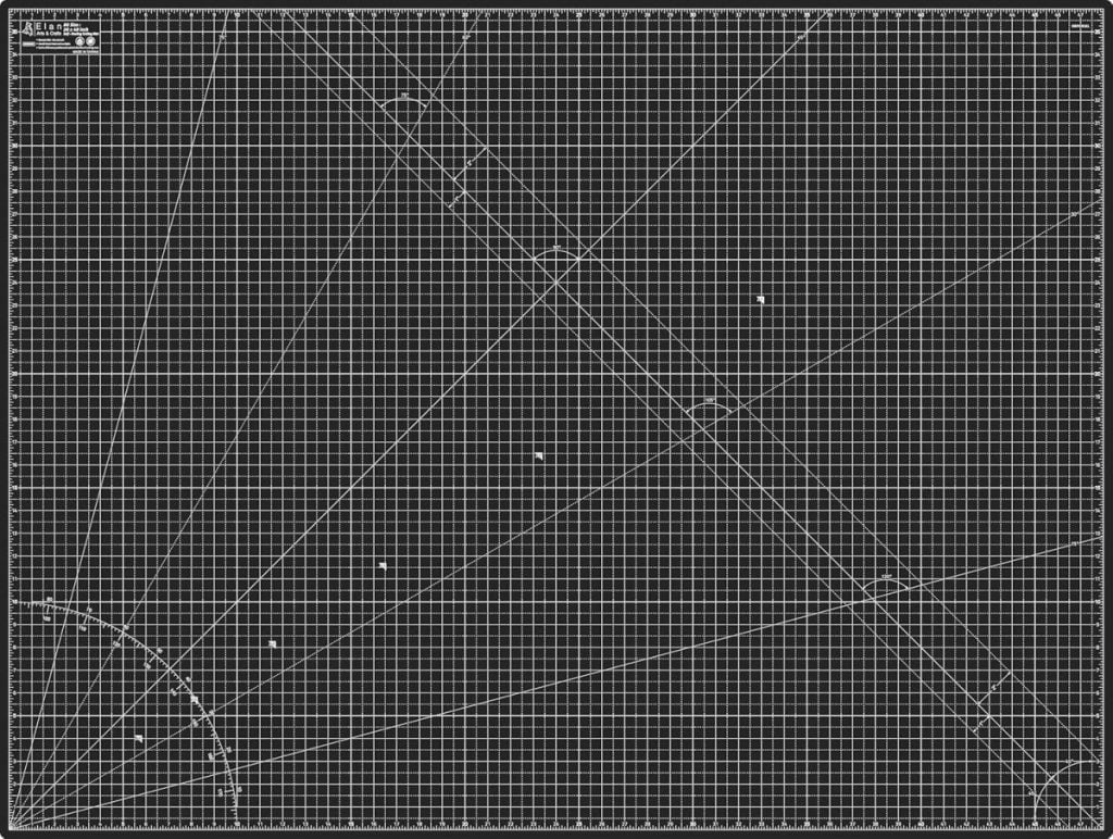 A large black self-healing cutting mat with a white grid, protractor lines, angles, and measurements marked in centimeters and millimeters.
