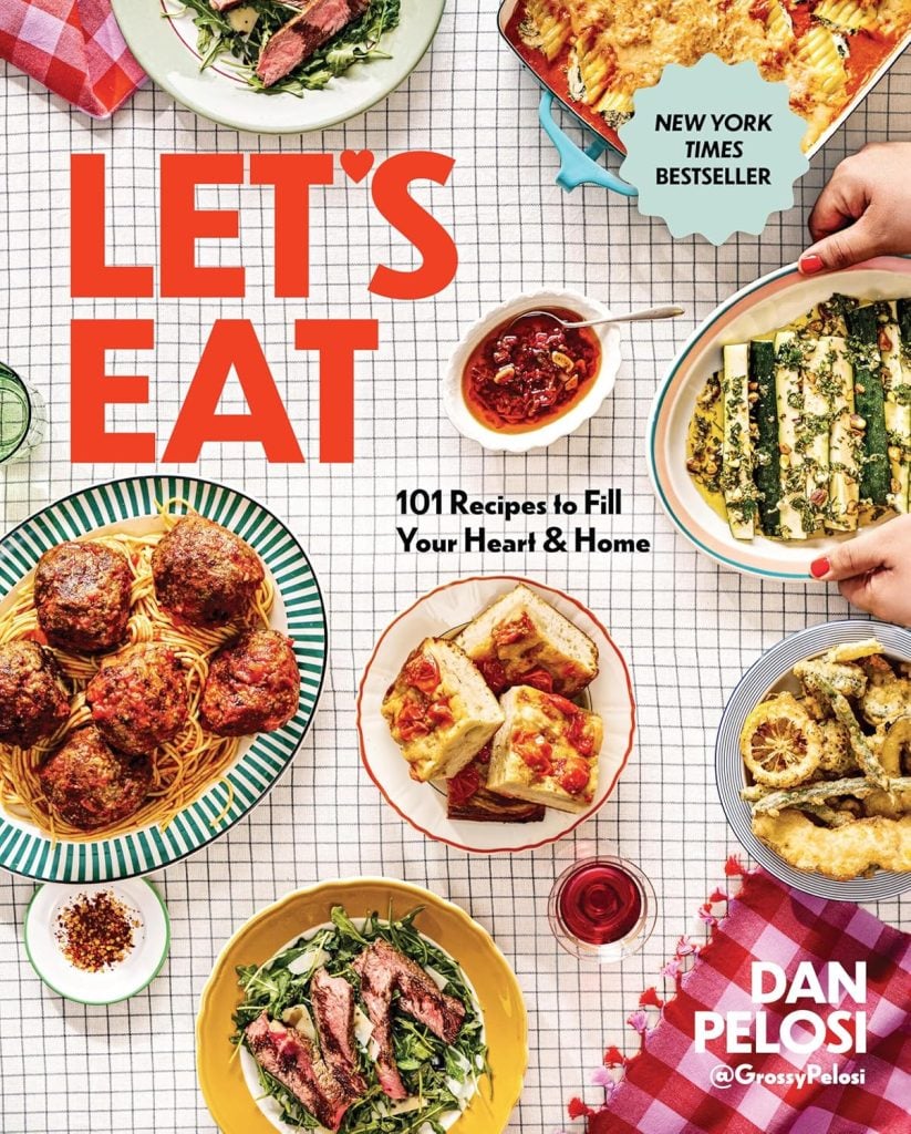 A table with various Italian dishes, including meatballs, lasagna, salad, and bread, featured on the cookbook "Let's Eat" by Dan Pelosi&mdash;inspiring Things To Do This Year for food lovers.