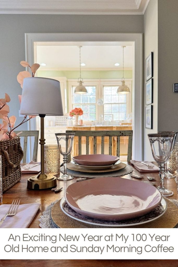 A dining table set with pink plates and crystal glasses is in the foreground; a bright, modern kitchen is visible in the background.