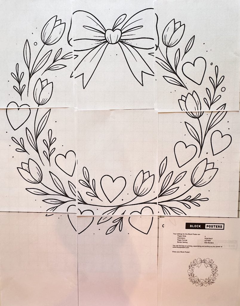 Line drawing of a heart-shaped wreath with leaves, tulips, and hearts, topped with a bow; design printed on six sheets of paper arranged in a grid.