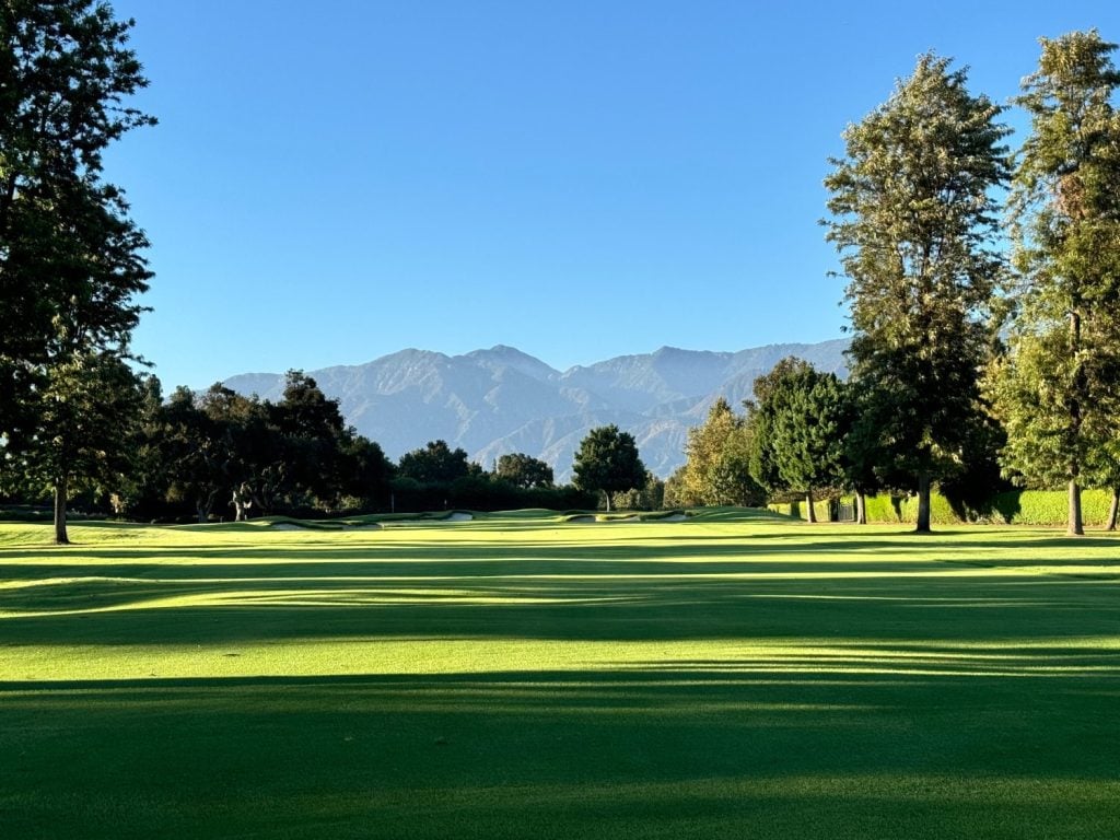 A golf course with trees and mountains in the background.