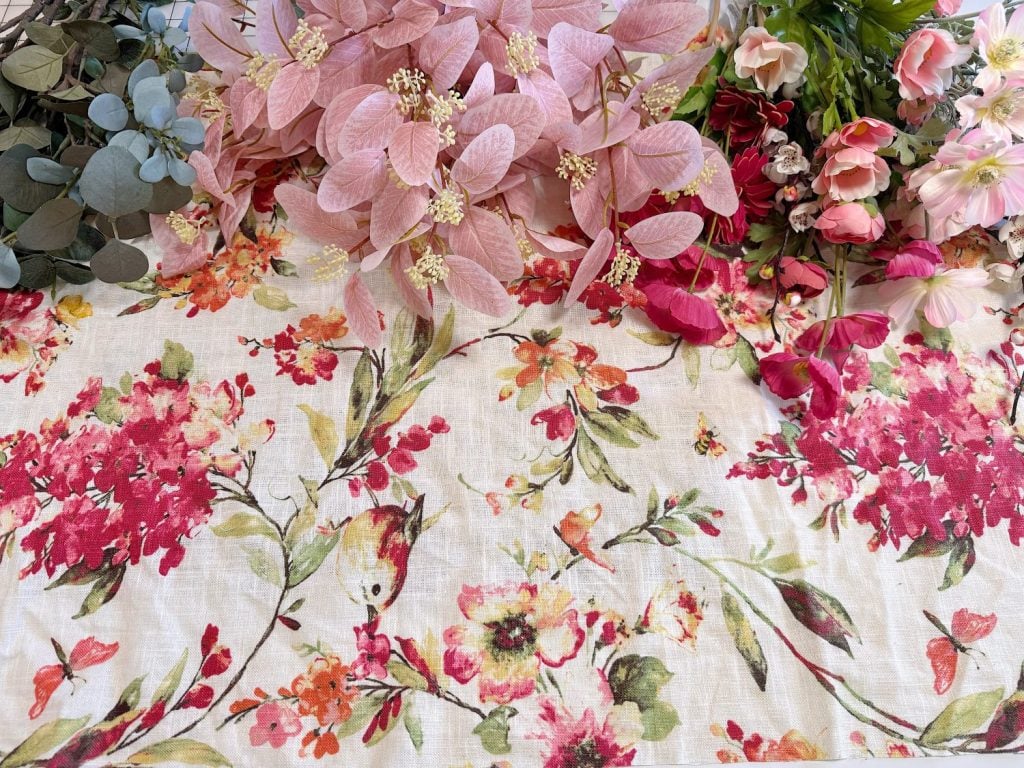 A floral-patterned fabric with artificial pink, red, and green flowers arranged along the top edge.