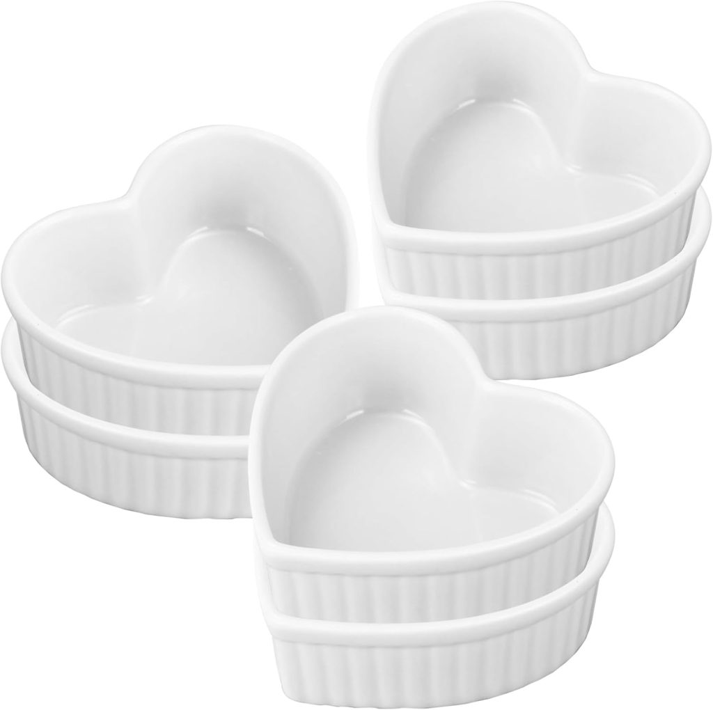 Four white ceramic heart-shaped ramekins are stacked in pairs against a plain background.