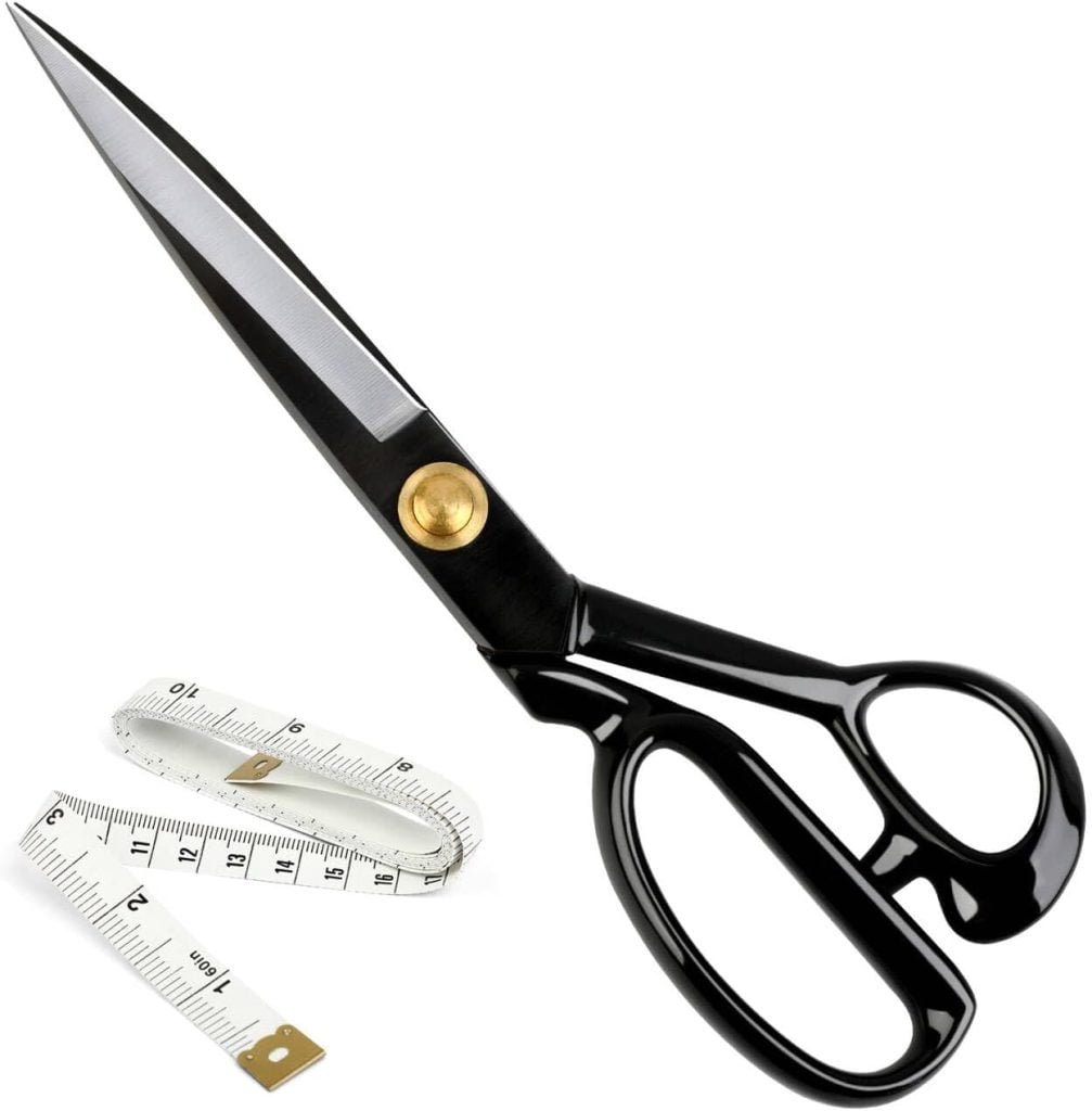 A pair of black-handled scissors with a gold pivot screw next to a rolled white measuring tape.