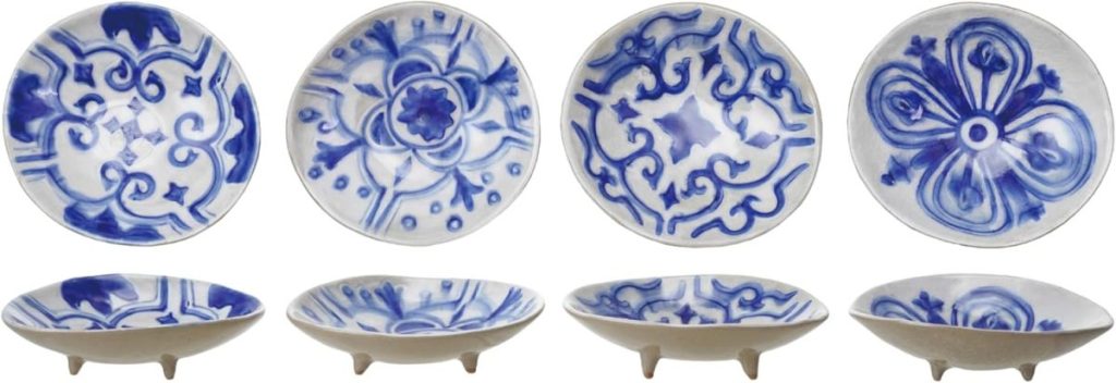 Four ceramic dishes with blue and white patterns, each displayed from a top and side view, set against a white background. Each dish has three small feet.