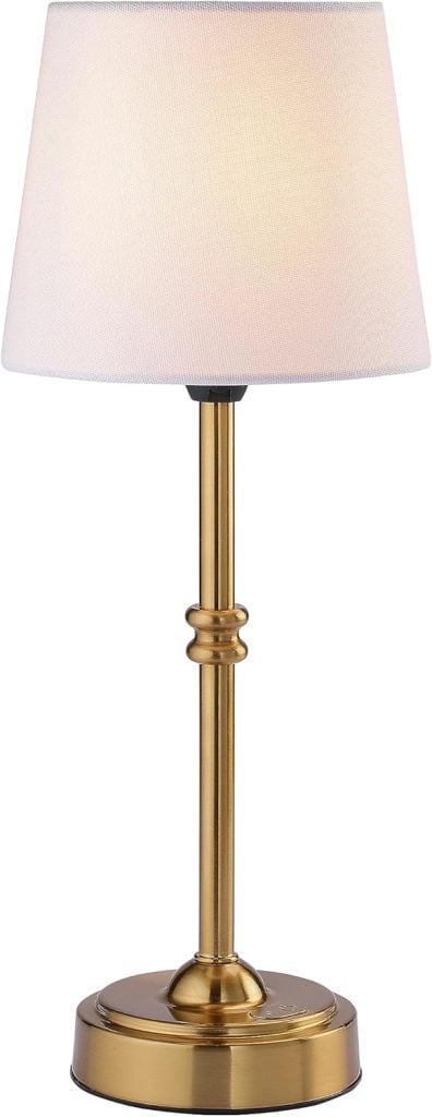 A brass table lamp with a round white fabric shade and a cylindrical base, turned on and illuminated.