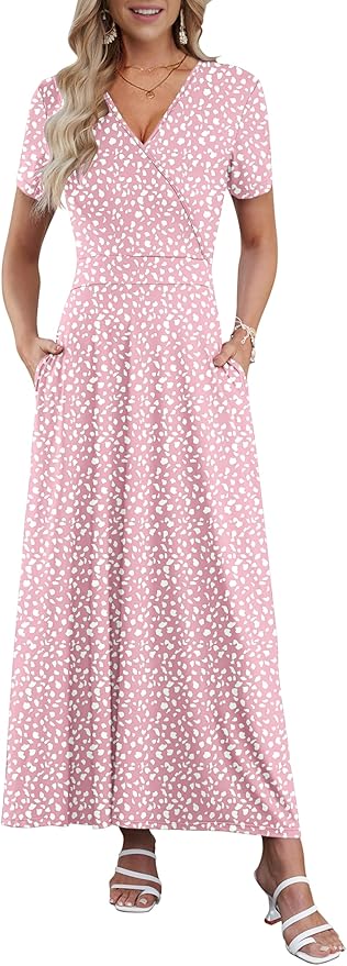 Woman wearing a pink and white patterned short-sleeve maxi dress with pockets, white sandals, and jewelry, standing against a plain background.