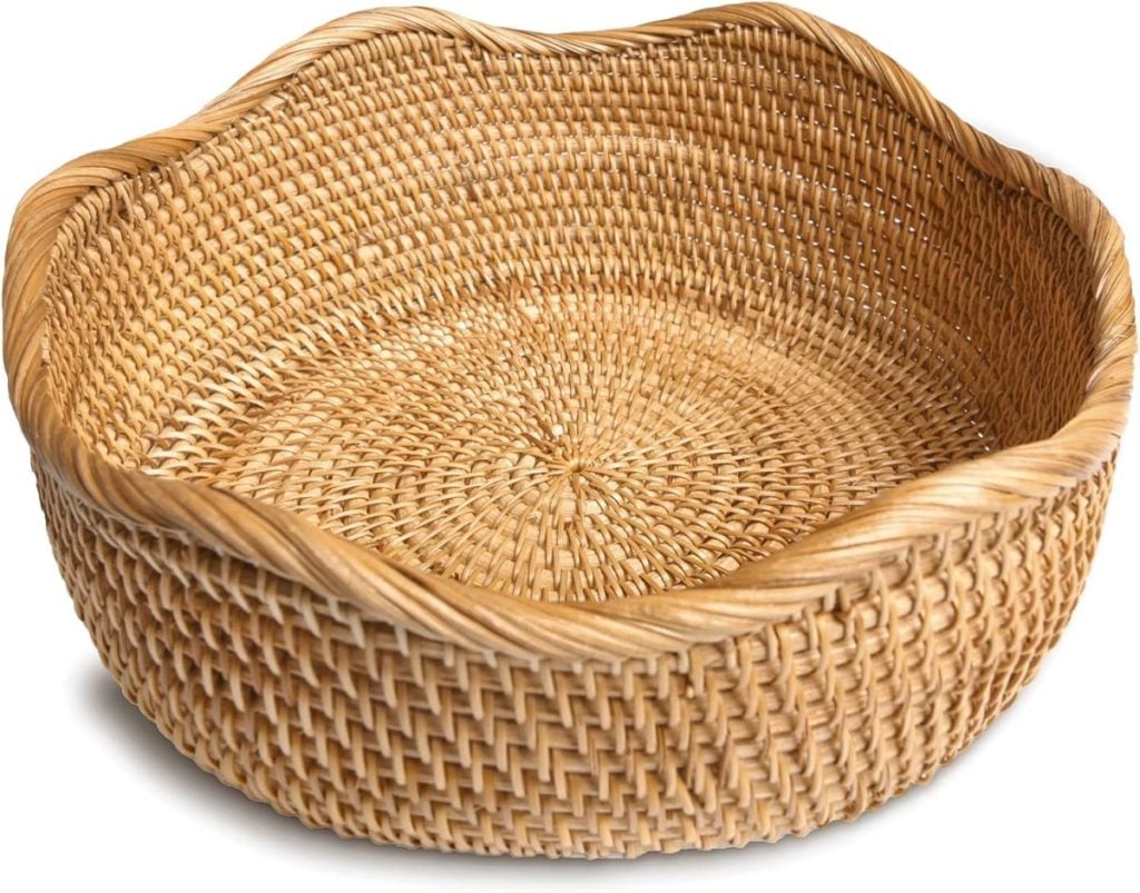 A round, empty woven wicker basket with a slightly wavy rim on a white background.