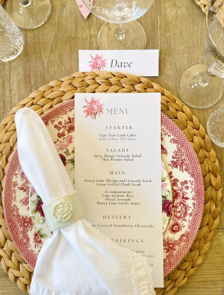 A table setting with a floral plate, woven placemat, folded napkin with a white napkin ring, and a printed menu card under a place card labeled "Dave.