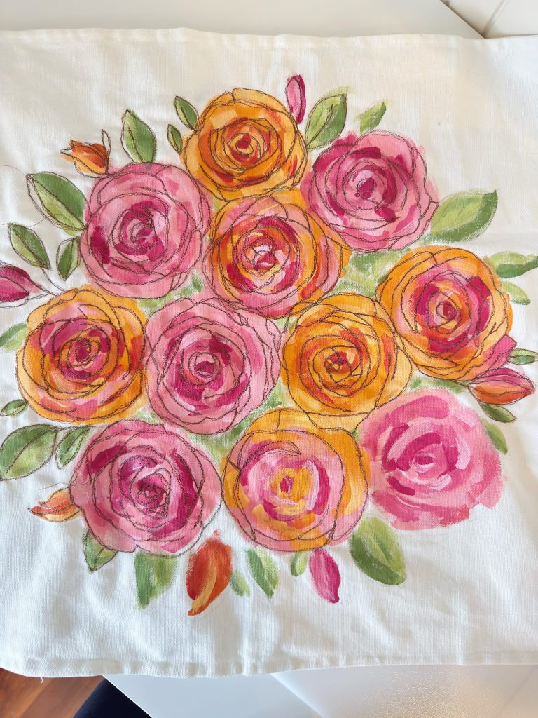 A cloth featuring a hand-painted floral design with pink and orange roses surrounded by green leaves.