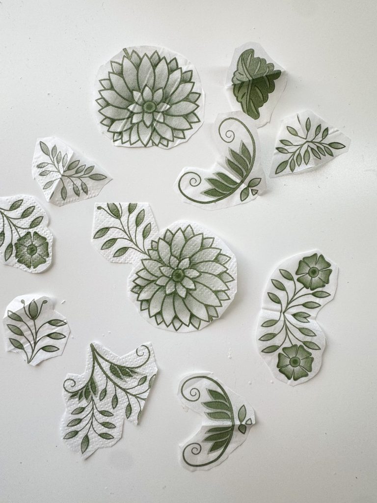 Green floral and leaf patterns on white paper, cut into various shapes and arranged on a white surface.