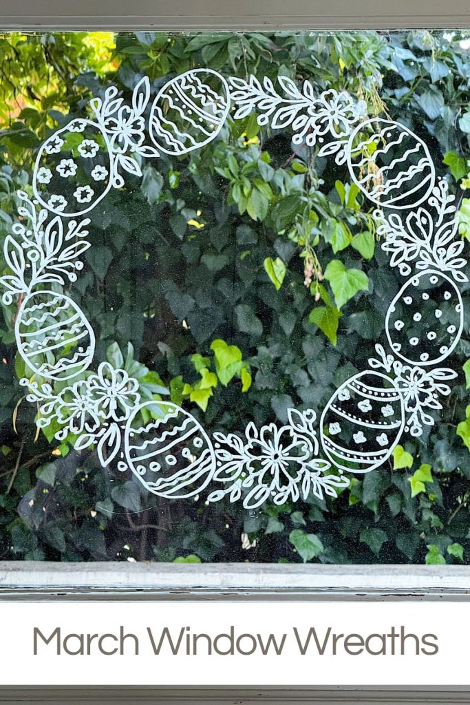 A white wreath design with decorated eggs is drawn on a window, with greenery visible outside. Text at the bottom reads "March Window Wreaths.