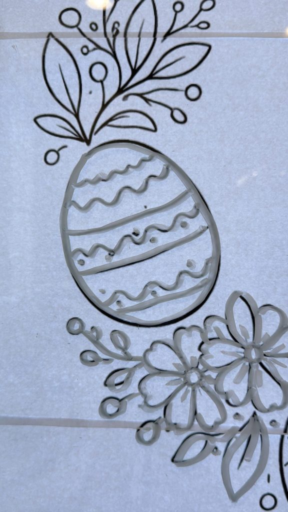 Black line drawing of a decorated Easter egg with leaves and flowers on a white background.