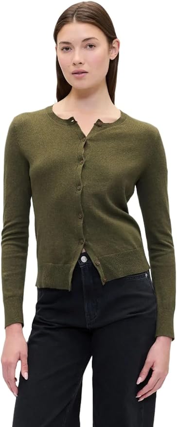 A woman wearing an olive green button-up cardigan and black pants stands against a white background, ready to refresh her style for the Amazon Big Spring Sale.