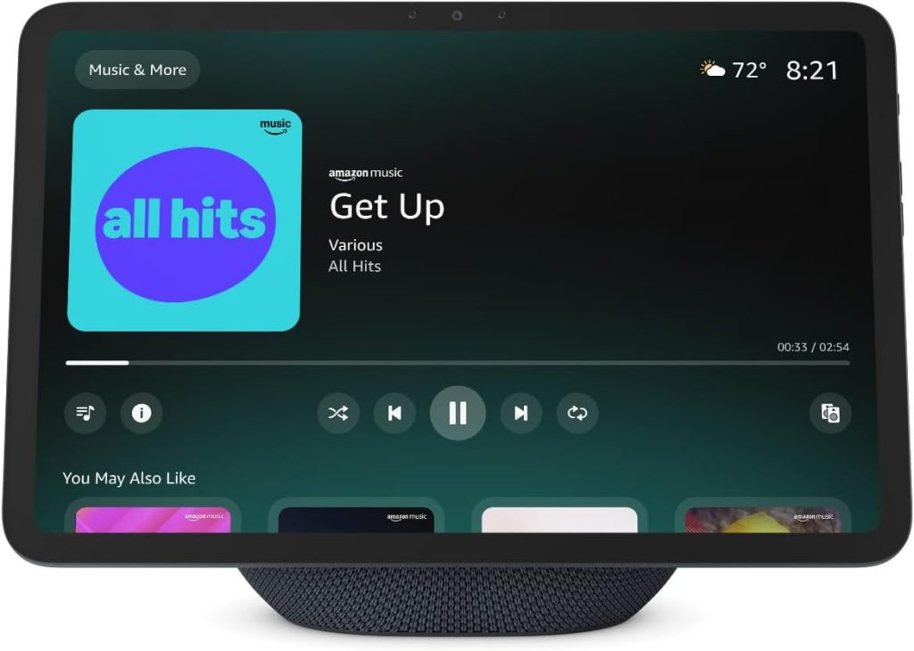 A smart display screen shows the Amazon Music app playing "Get Up" from the playlist "All Hits," with playback controls, album art, song suggestions, and a banner highlighting the Amazon Big Spring Sale.