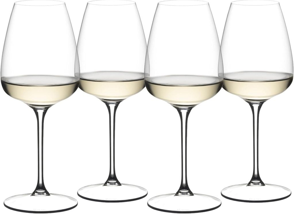 Four clear wine glasses partially filled with white wine, arranged in a row against a plain white background.