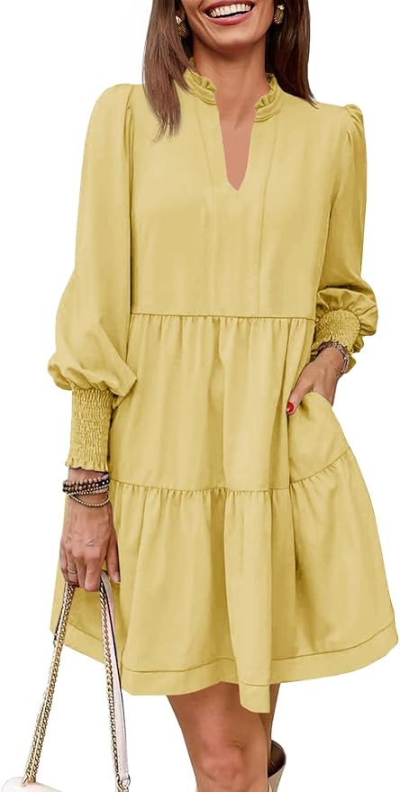 Woman wearing a loose-fitting, long-sleeve, yellow tiered mini dress with ruffled neckline and smocked cuffs, holding a chain-strap purse&mdash;perfect for refreshing your look for the Amazon Big Spring Sale.