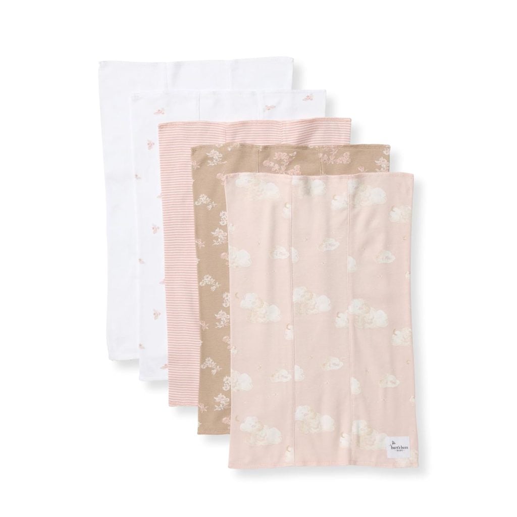 Five folded baby burp cloths in pastel colors and patterns, including plain white, pink stripes, brown with flowers, and pink with clouds and sheep.
