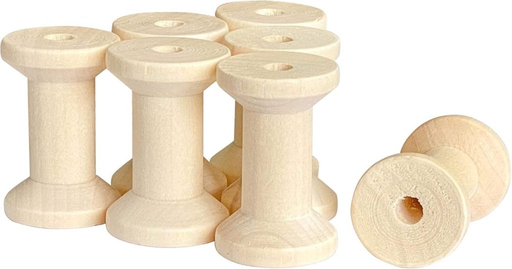 Seven unfinished wooden spools are grouped together, with one spool lying on its side in front.
