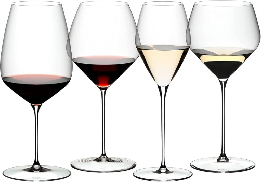 Four wine glasses, two filled with red wine and two with white wine, are arranged side by side on a plain white background.