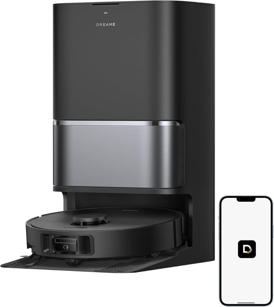 A black robot vacuum docked at its charging station, with a smartphone displaying the Dreame app icon&mdash;perfect for smart cleaning during the Amazon Big Spring Sale.