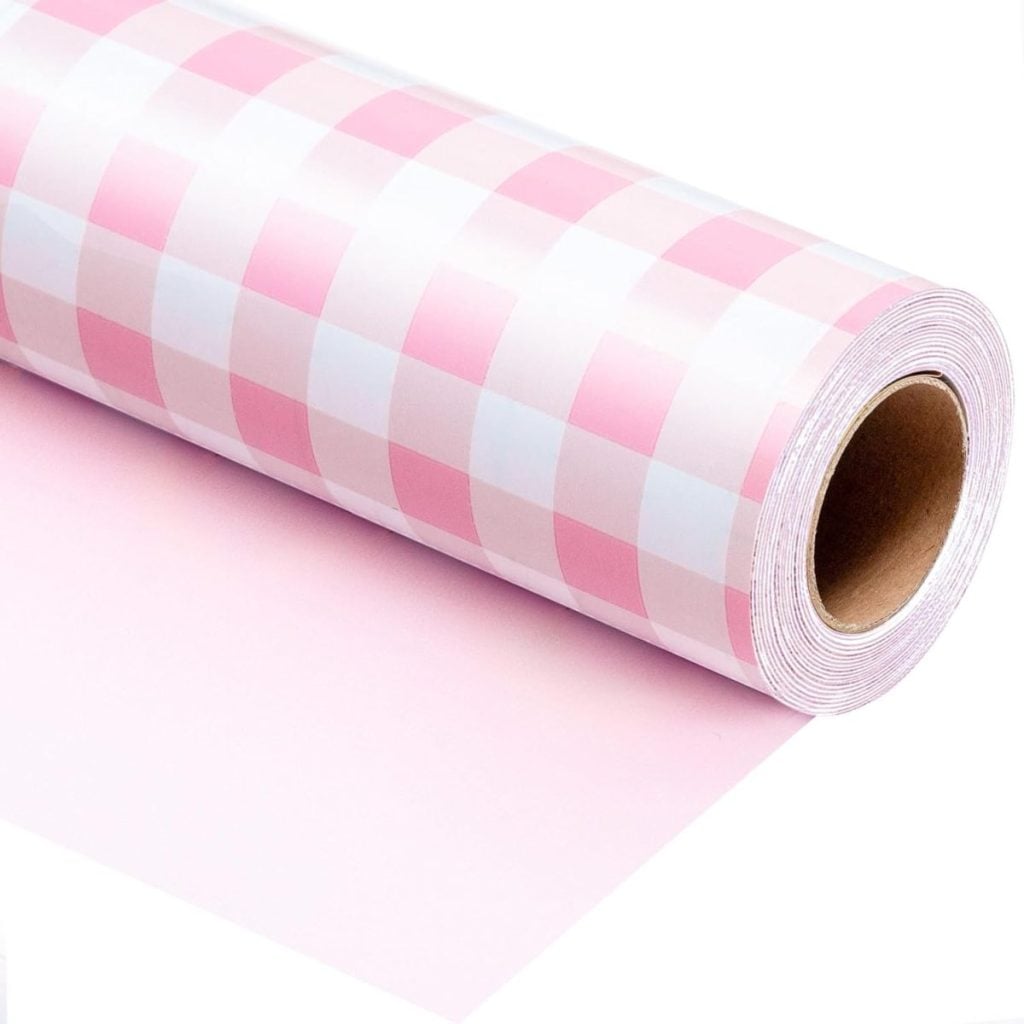A roll of pink and white checkered wrapping paper partially unrolled on a flat surface.