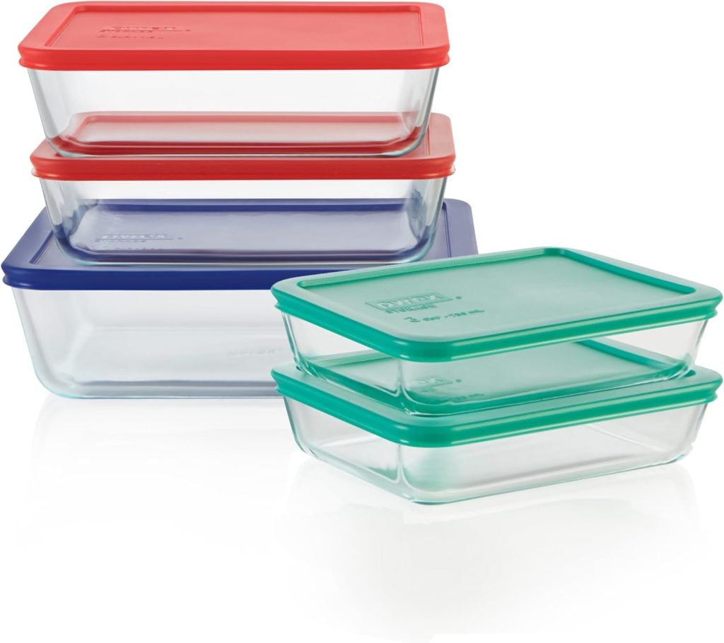 Six rectangular glass food storage containers with colored lids&mdash;two red, two green, and two blue&mdash;stacked in two groups on a white background.
