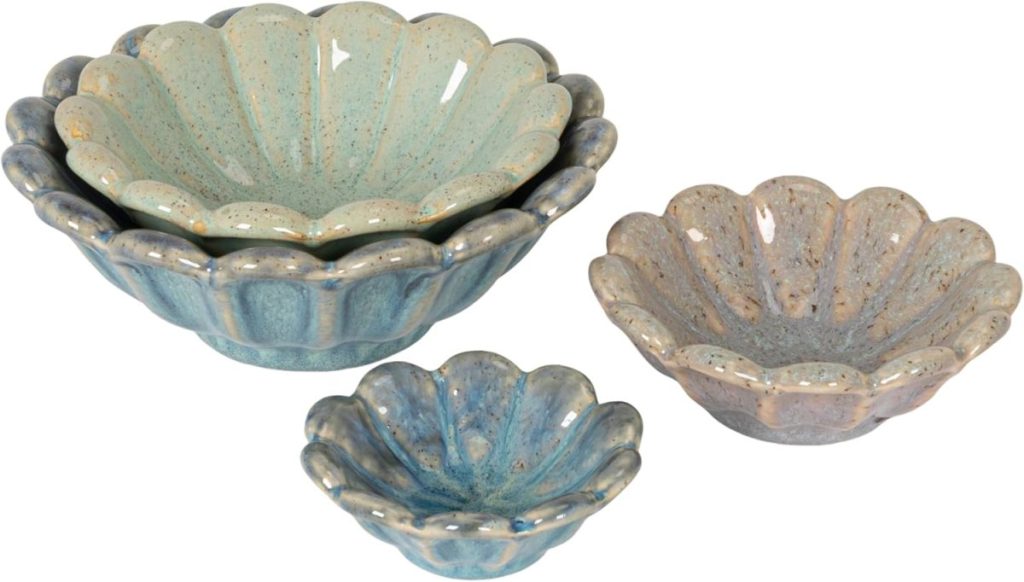 Four ceramic bowls in pastel colors, shaped like flowers, are nested and arranged in pairs on a white background.