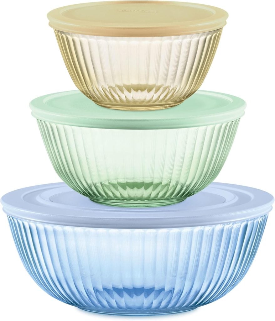 Three ribbed glass bowls in yellow, green, and blue, stacked by size with matching pastel lids; each bowl has a different color and lid.