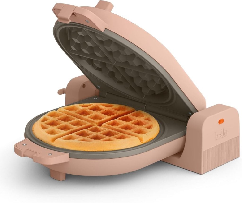 A pink electric waffle maker with its lid open, showing a freshly baked waffle inside&mdash;ideal for your kitchen and a must-have find during the Amazon Big Spring Sale.