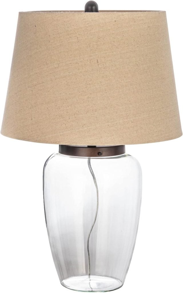 A table lamp with a clear glass base and beige fabric lampshade, featuring a visible cord inside the base&mdash;perfect to brighten your home during the Amazon Big Spring Sale.