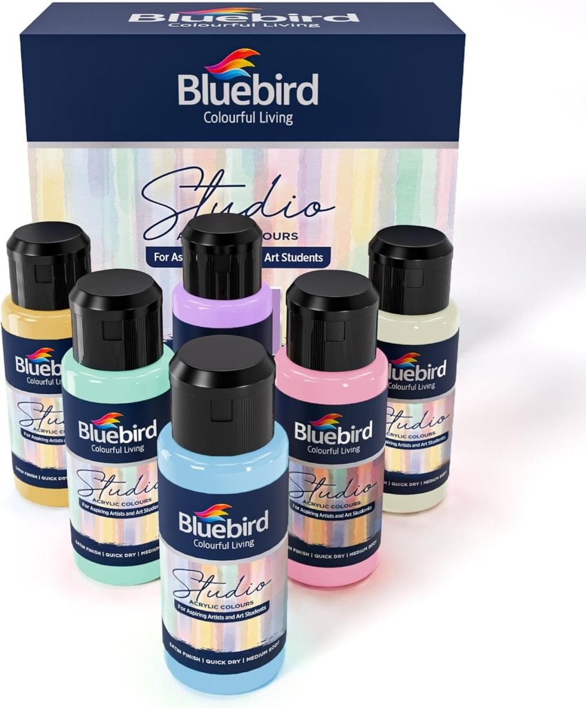 Six bottles of Bluebird Studio acrylic colours are arranged in front of their packaging box, which features a colorful design and the Bluebird Colourful Living logo.