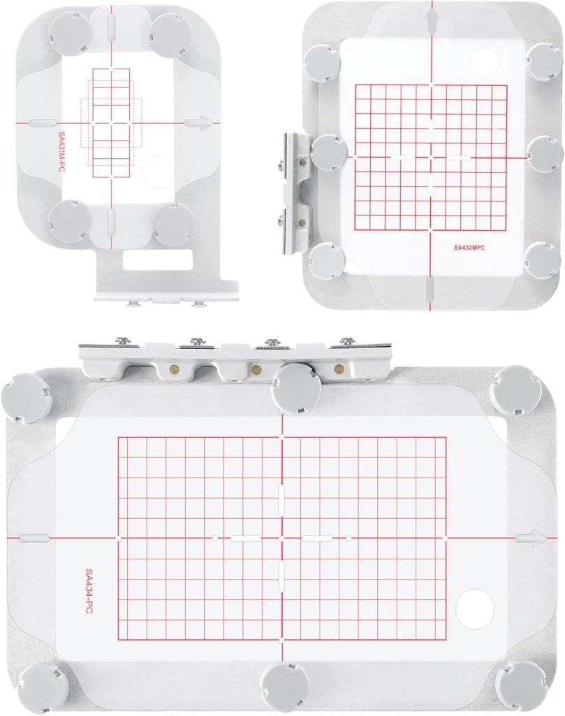 Three rectangular embroidery hoops with clear plastic grids, each featuring red alignment lines and adjustment knobs, are displayed on a white background.