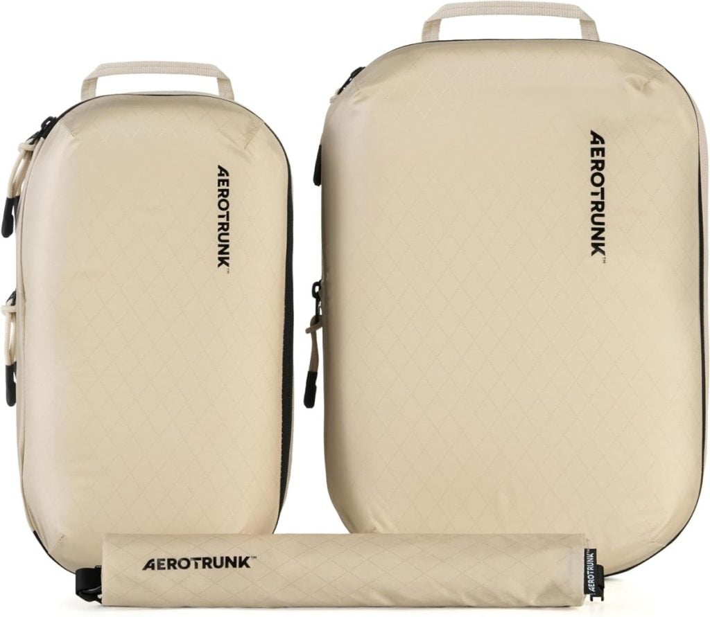Two beige Aerotrunk travel packing bags of different sizes stand upright with a rolled-up item in front, all featuring the Aerotrunk logo in black&mdash;perfect for organizing your essentials during the Amazon Big Spring Sale.