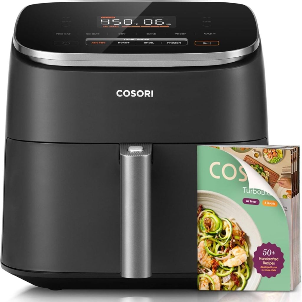 A black Cosori air fryer with a digital display, shown next to a recipe booklet featuring images of dishes&mdash;perfect for discovering new favorites during the Amazon Big Spring Sale.