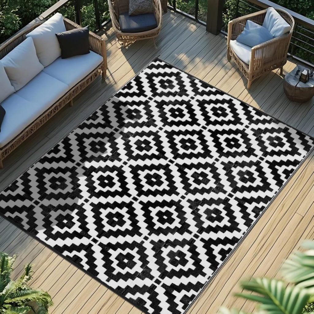 Black and white geometric patterned rug placed on a wooden outdoor deck, surrounded by patio seating and greenery&mdash;perfect for refreshing your space during the Amazon Big Spring Sale.